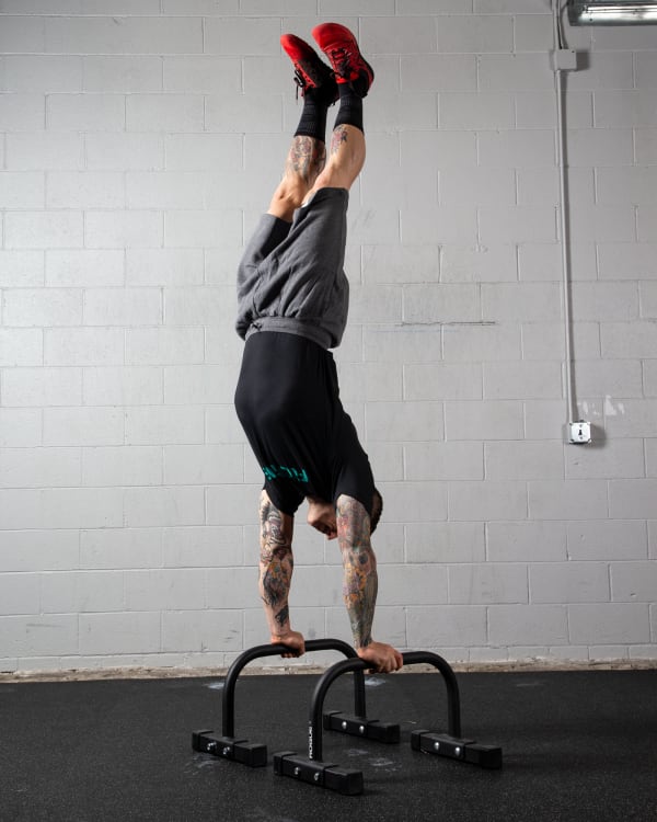 Athlete holding a handstand on the Rogue Bolt Together Parallette Set
